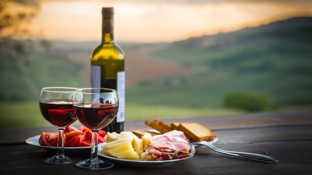 Wein zum Essen: Mit Rotwein gefüllte Weingläser zu Schinken und Käse